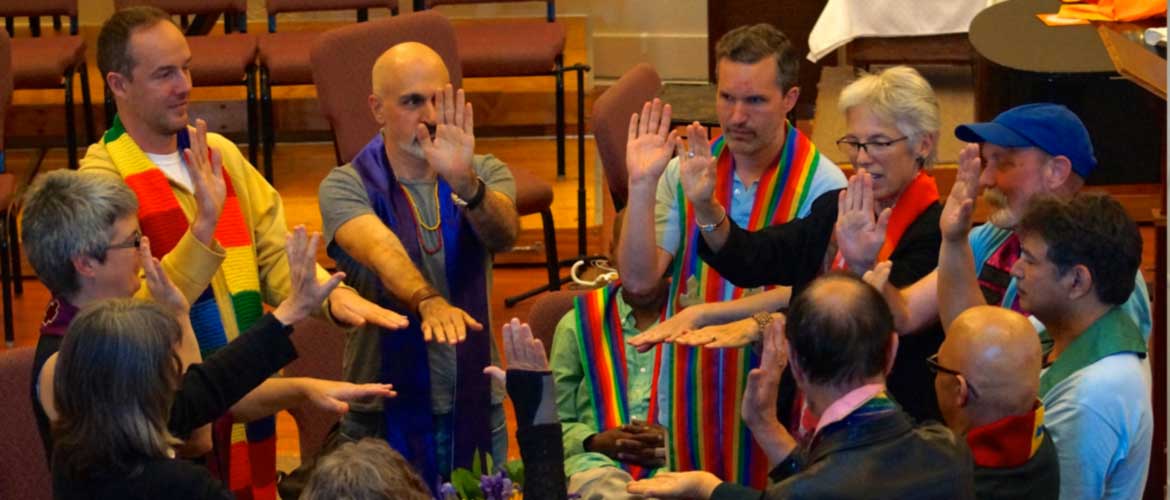 Queer Eucharist folks all wearing stoles and gathered in a circle with arms reaching towards the center